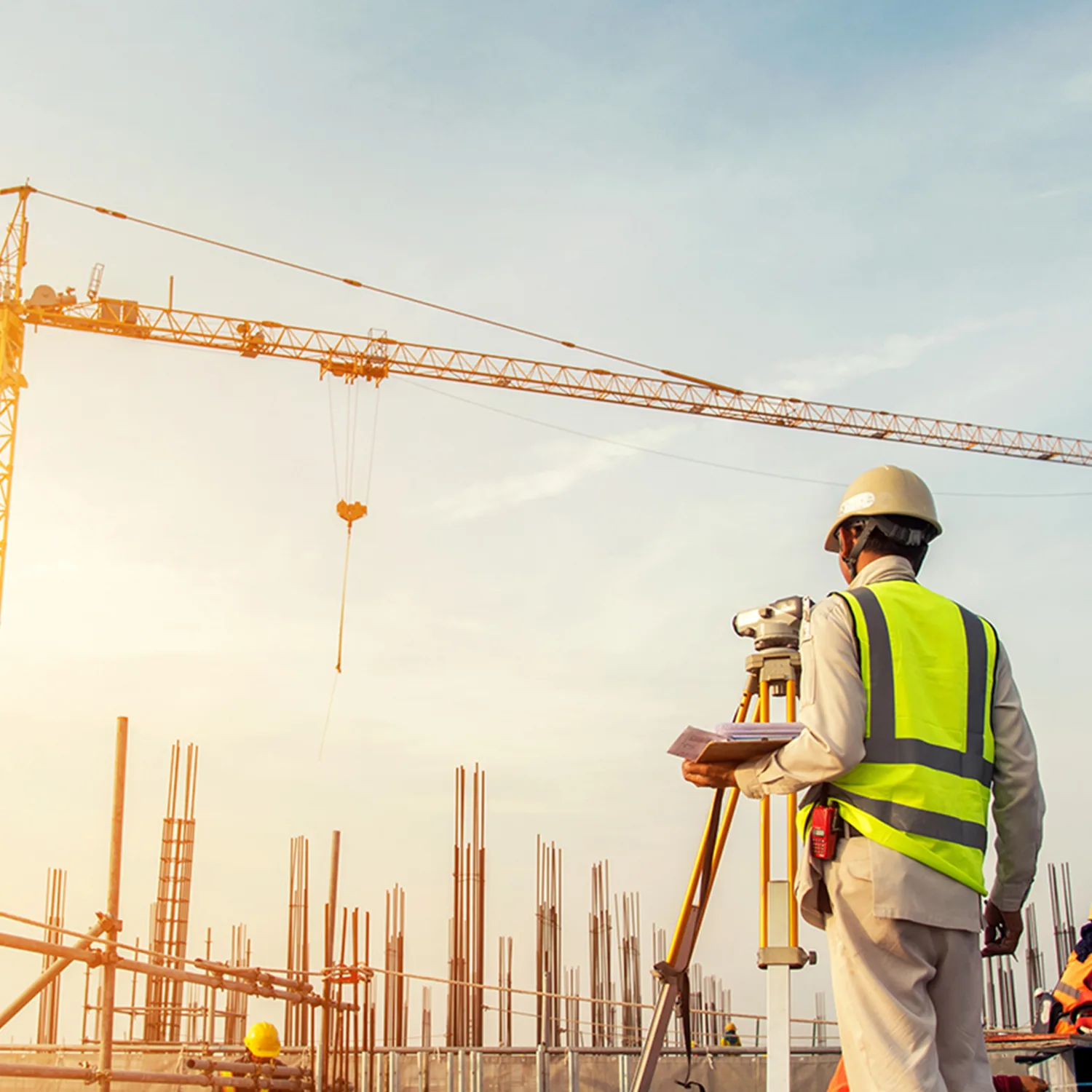 Construction workers on a building site with a yellow crane against a sunlit blue sky