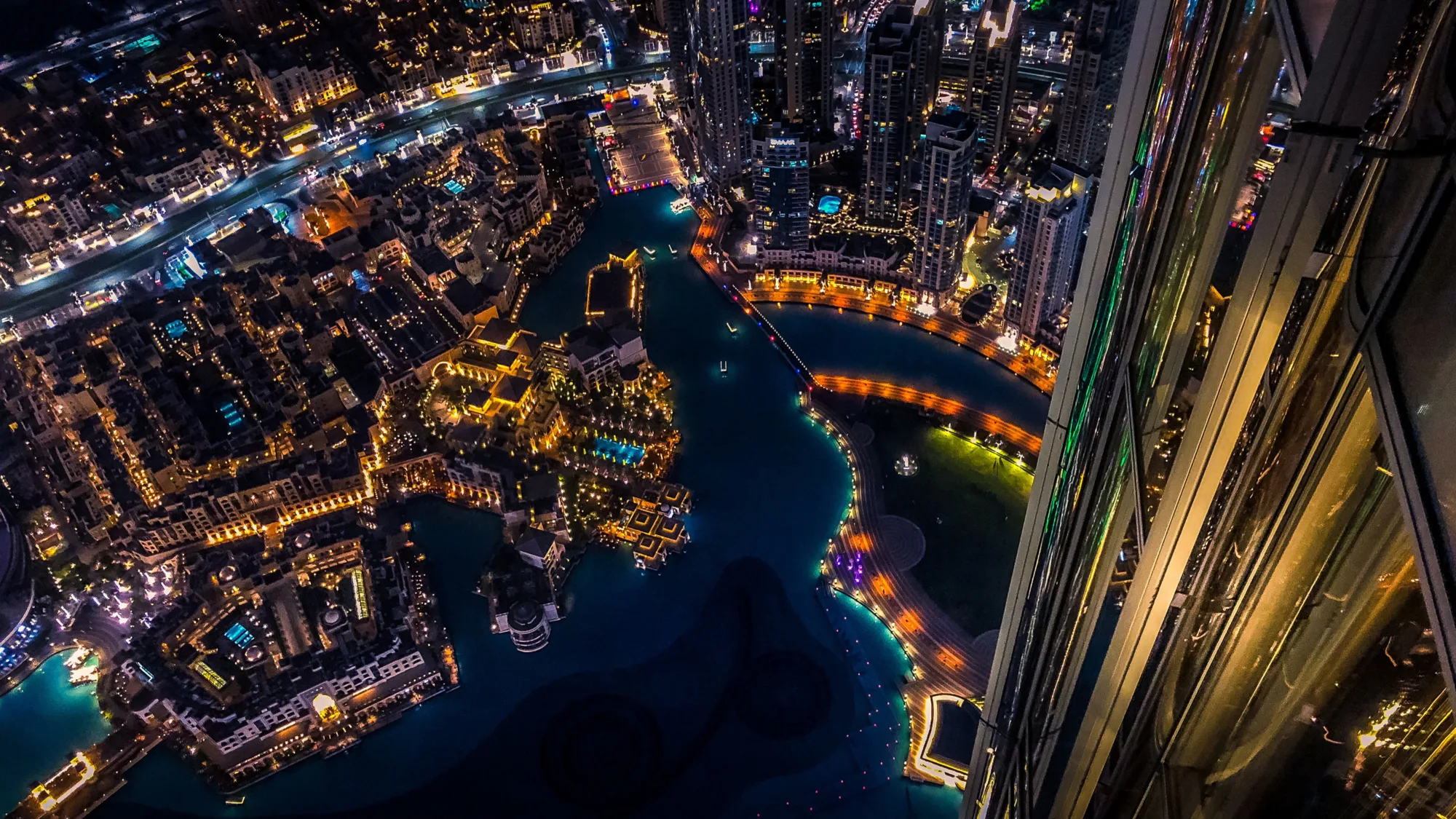 Arial view at night of Dubai looking down over lit buildings and water