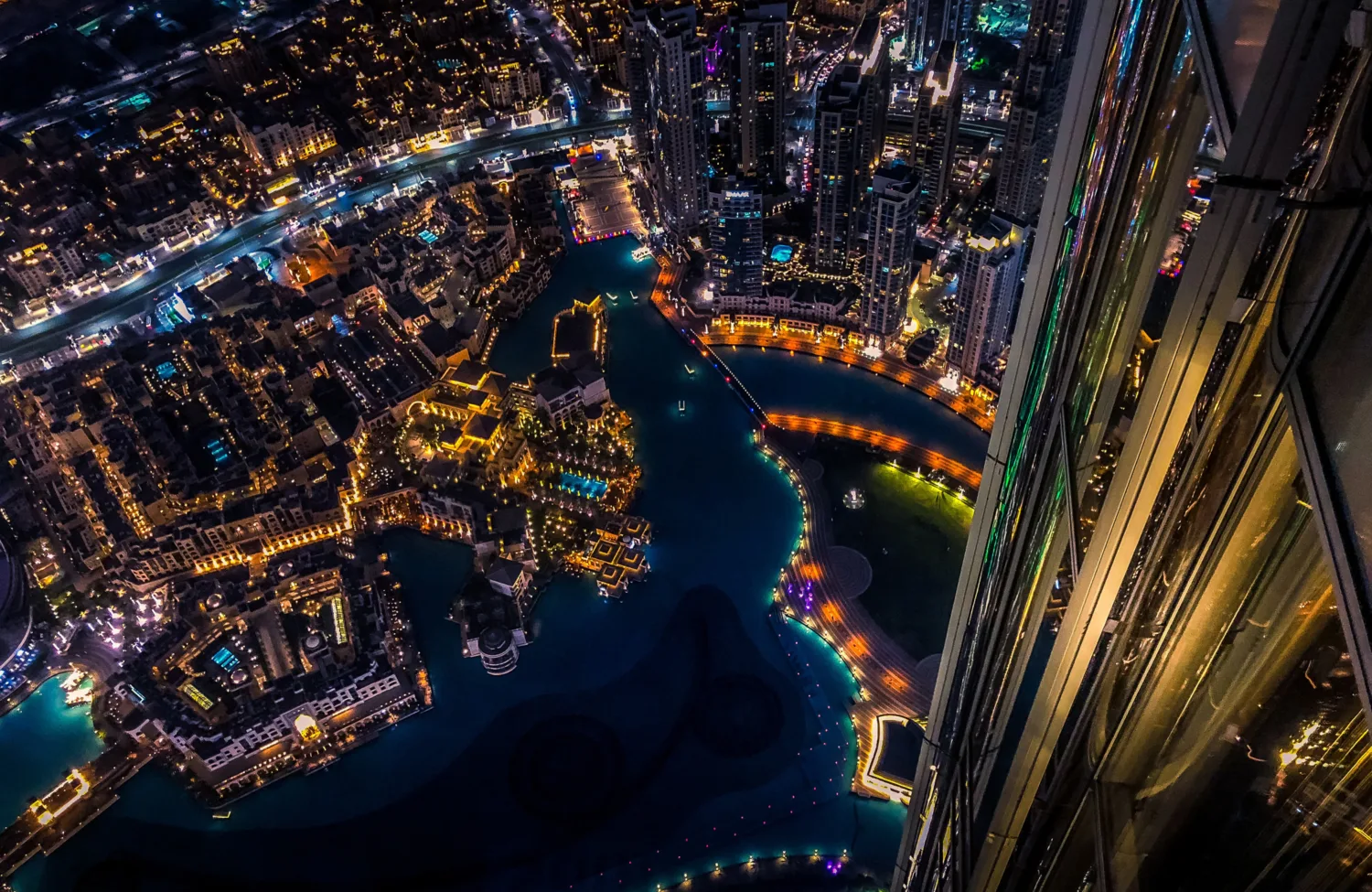 Arial view at night of Dubai looking down over lit buildings and water