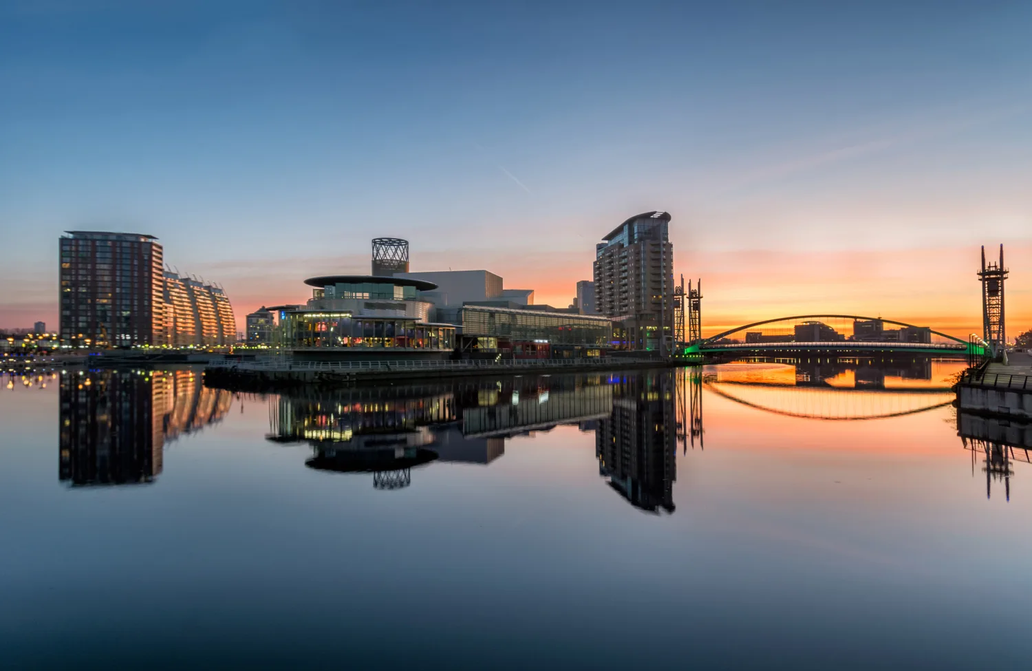 Blue and orange sky reflected in clear water at Salford Docks