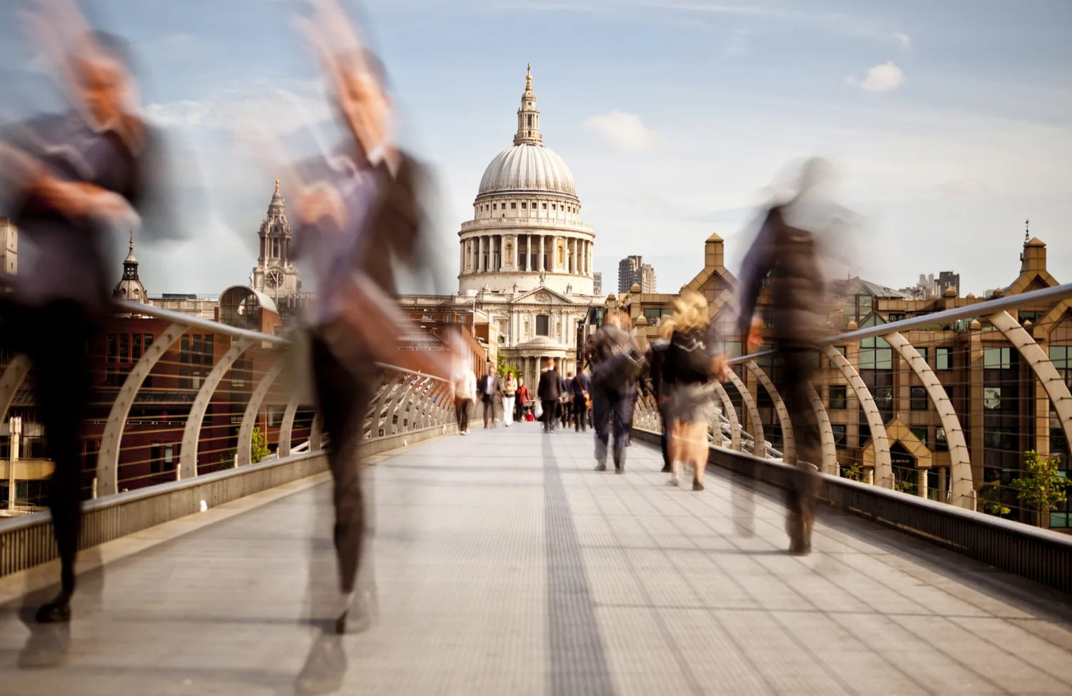 People walking across the millennium bridge with St Paul's Cathedral in the background